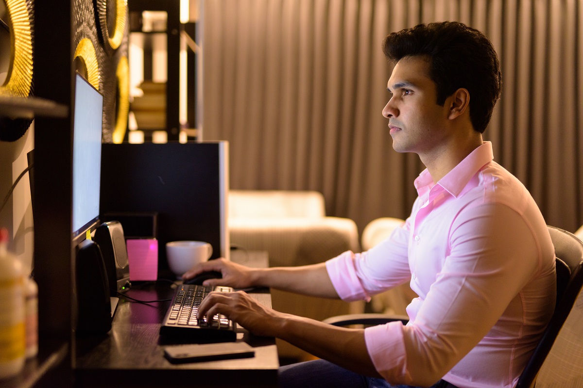 Young handsome Indian businessman working overtime at home late at night