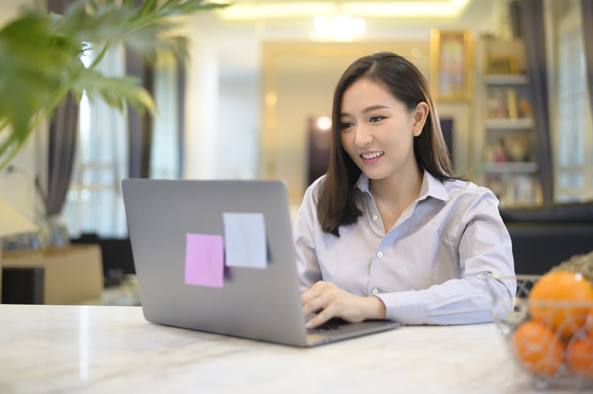 A beautiful Asian business woman is working with her computer at home , Telecommunication , social distancing ,Work from home concept